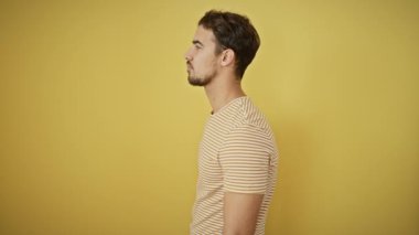 Kendinden emin gülümseyen çizgili tişörtlü İspanyol adam doğal olarak poz veriyor. Aerodinamik sarı arka planda gelişigüzel duran bir profil..