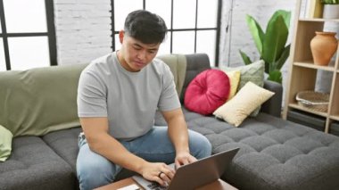 Konforlu bir evde çalışan Asyalı genç bir adam, bir video görüşmesi sırasında webcam 'e' hayır 'işareti yapıyor..