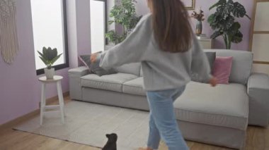 Neşeli bir kadın rahat bir oturma odasında neşeli şivavasıyla dans ediyor..