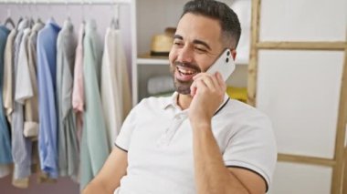 Neşeli İspanyol bir adam akıllı bir telefonla konuşuyor. Parlak bir giyim odasında, moda, iletişim ve yaşam tarzını resmediyor..