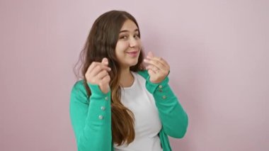 Küstah genç İspanyol kadın güven içinde para jestini canlandırıyor, maaş talep ediyor, canlı pembe arka planda tek başına duruyor, iş hayatının başarısını işaret ediyor.