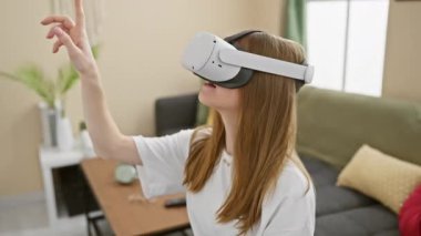 Genç bir kadın modern oturma odasında sanal gerçeklikten zevk alıyor. Kapalı alandaki yenilikleri ve cazibesini ifade ediyor..