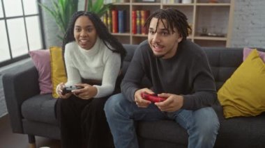 Neşeli bir çift, rahat bir oturma odasında birlikte video oyunları oynuyor, rahatlık ve arkadaşlık tasvir ediyorlar..