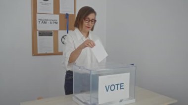 Seçim sırasında oy sandığında kapalı alanda oy verirken gülümseyen orta yaşlı bir kadın.