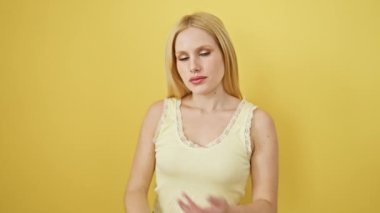 Şen şakrak sarışın tişörtlü, çapraz kollu, sarı arka planda neşeli bir sırıtış