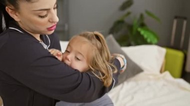 Sıcak bir yatak odasında, bir kadın ve küçük kızı arasında sevgi ve sevgi dolu bir anı paylaşıyorlar..