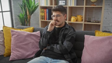 Yakışıklı, gözlüklü ve bıyıklı, rahat oturma odasında oturmuş İspanyol bir adam..