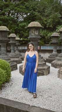 Güzel kalçalı, gözlüklü, gözlerinde neşe parıldayan, huzur içinde Huzurlu Ueno Park Tapınağı 'nda yürüyen bir Latin. Kamera, Tokyo 'nun masmavi gökyüzünün altında ilerlerken onun neşeli gülümsemesini yakalar..