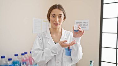 Elinde mavi sıvıyla deney tüpü tutan kadın bir bilim adamı laboratuvarda güvenle duruyor..