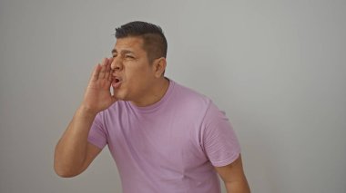 Pembe tişörtlü İspanyol bir adam beyaz bir arkaplan karşısında bağırıyor, iletişim tasvir ediyor ya da arıyor..