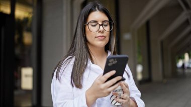 Madrid sokaklarında akıllı telefon kullanarak gülümseyen güzel İspanyol kadın.