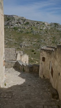 Avrupa 'daki kayalık tepelerin manzarası ile, materyada, bazilikada, İtalya' da antik taş ara sokaklar, açık mavi gökyüzü altında tarihi mimari sergileniyor..