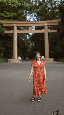 Neşeli, güzel, gözlüklü İspanyol kadın kendinden emin bir şekilde poz veriyor, Tokyo 'nun meiji türbesine gülümsüyor, mutluluğu şaşırtıcı gülüşünün içinden açıkça yayılıyor.