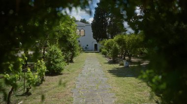 Bereketli bir bahçeden geçen manzaralı patika Puglia, İtalya 'da tarihi bir villaya çıkıyor. Parlak bir gökyüzü altında Akdeniz florası ve klasik mimari sergileniyor..