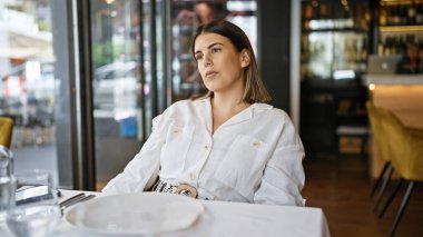 Genç, güzel, İspanyol bir kadın restoranın masasına bakıyor.