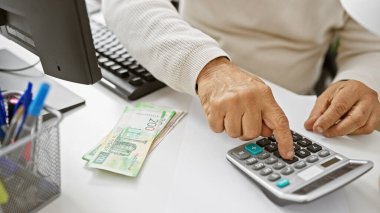 Orta yaşlı bir adam masasında Rus para birimi olan bir ofiste mali hesaplar yapar..