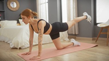 Odaklanmış bir kadın modern bir yatak odasında yoga yapıyor, sağlık ve ev içi egzersizleri vurguluyor..