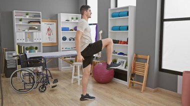 Yakında tekerlekli sandalyesi olan, modern bir rehabilitasyon kliniğinde egzersiz yapan yakışıklı bir genç..