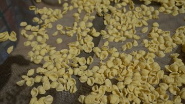 Orecchiette pasta drying outdoors in bari, puglia, italy, showing traditional italian culinary methods during sunny weather on a mesh tray. clipart