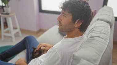 Düşünceli genç bir İspanyol adam evinde bir kanepede gevşiyor. Kahverengi bir kedi yavrusunu nazikçe tutuyor. Kapalı bir odada sükuneti somutlaştırıyor..