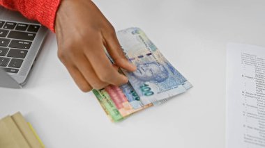 Modern ofis ortamında Güney Afrika Rand 'ini idare eden Afrikalı bir kadın..