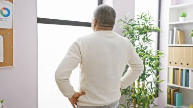 Orta yaşlı bir İspanyol 'un ofis ortamında pencereden dışarı bakıp profesyonelliği ve tefekkürü somutlaştırması..