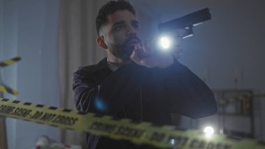 İçeride sakallı, elinde silah ve el feneri olan İspanyol bir adam var.