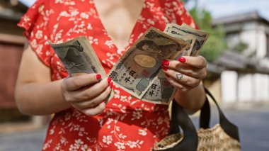 Young woman's hands, busy counting yen banknotes in the traditional streets of kyoto, a caucasian immersed in japanese banking and finance clipart