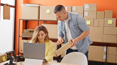 Kadın ve erkek dış ticaret işçileri ellerinde bir paketle ofiste konuşuyorlar.