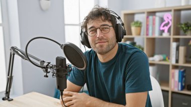 Stüdyoda sakallı, kulaklık takmış mikrofona konuşan İspanyol bir adam..