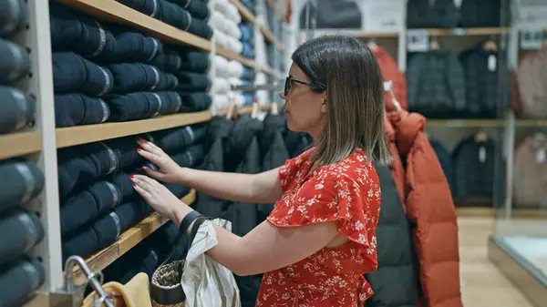 stock image Fashion passion! beautiful hispanic woman with glasses choosing chic clothes in a retail store. portrait of a young, brunette shopper shopping at a boutique in the mall.