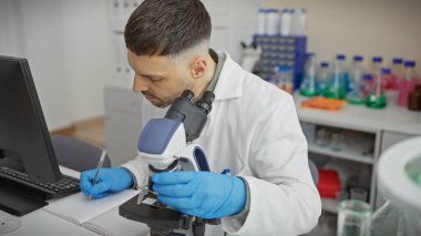 Laboratuvardaki İspanyol adam mikroskop kullanarak bilimsel araştırma ve sağlık hizmetlerine odaklanıyor..