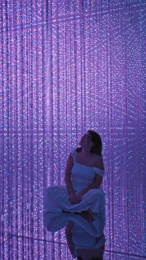 Gülümseyen güzel İspanyol kadın modern müzede fütürist sergiler sergiliyor. Lazerler, ışıklar, en iyi yenilikler.!