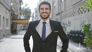 Takım elbiseli yakışıklı İspanyol bir adam. Şehir caddesinde güvenle gülümsüyor..