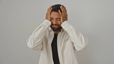 Üzgün, sakallı, beyaz arka planda günlük kıyafetler giyen Afro-Amerikan bir adam.