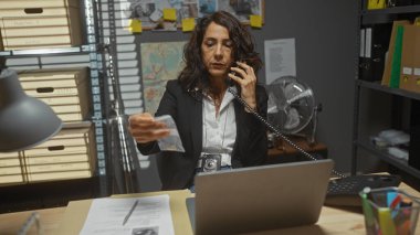 Olgun kadın dedektif, bir ofiste çalışıyor. Bir telefon görüşmesinde, etrafında dosyalar ve dizüstü bilgisayarla kanıtları inceliyor..