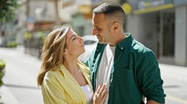 Erkek ve kadın bir arada durarak gülümsüyor.