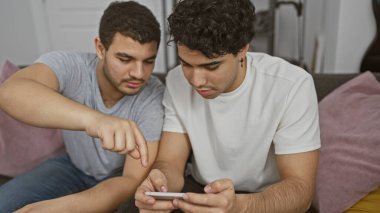 İki adam bir anı paylaşıyor, akıllı telefona bakıyor, arkadaşlığı ve bağlantıyı somutlaştırıyor..