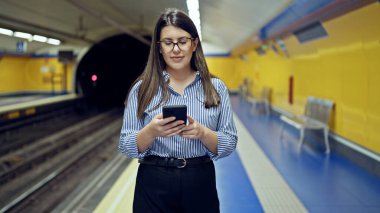 Madrid metro istasyonunda akıllı telefon kullanan güzel İspanyol bir kadın metroda bekliyor.