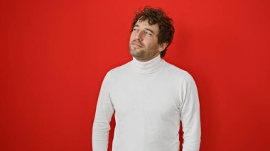 Düşünceli, sakallı İspanyol bir adam kırmızı arka planda poz veriyor..