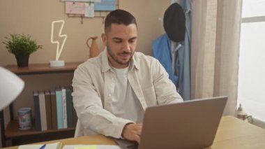 Evinde rahat bir oturma odasında dizüstü bilgisayarla çalışan genç bir İspanyol..