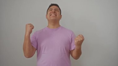 Genç İspanyol adam başarıyı kutluyor, kollarını kaldırıp beyaz arka planda soyutlanmış bir şekilde evet diyor.