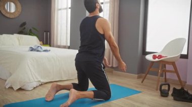 Yatak odasında yoga minderinin üzerinde uzanan bir adam. Huzurlu bir yuva ortamının ortasında..