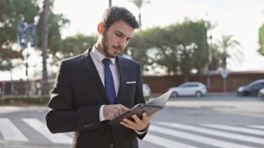 Yakışıklı sakallı iş adamı güneşli şehir caddesinde tablet kullanıyor.