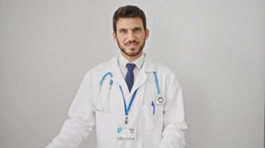 Kendine güvenen genç İspanyol bir adam, muhtemel bir doktor, neşeli bir şekilde arkasını işaret eden, parlak bir gülümseme, kıtır kıtır beyaz bir arka planda izole edilmiş..