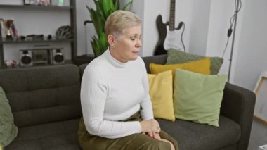 Bir kadın ve bir erkek sıcak bir anı paylaşıyor, onu sarı bir battaniyeye sararken, bir kanepede, kapalı bir yerde.