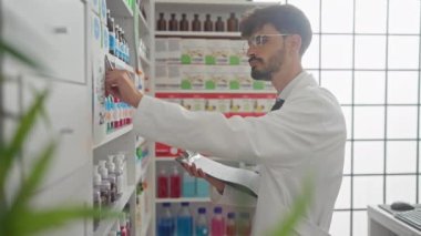 İyi aydınlatılmış bir eczanede eczacı olarak çalışan yakışıklı bir İspanyol envanteri doldurup kontrol ediyor..