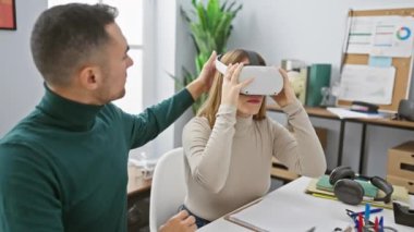 VR kulaklıklı kadın, modern ofisteki bir adam tarafından yönlendirildi. Teknolojiyi iş yenilikleri için kullanıyor..