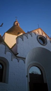 Büyüleyici alberobello, puglia, italyan, açık mavi gökyüzüne karşı eşsiz konik çatılar sergilenen geleneksel beyaz taş evlerin pitoresk manzarası.