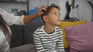 Anne oğlunu oturma odasında tımar ediyor. Aile bakımını gösteriyor. Kadın ve çocuk arasındaki kapalı mekan anlarını gösteriyor.